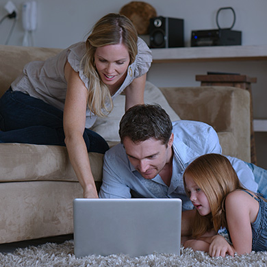 Familia interactuando con un ordenador portatil junto a un sofá