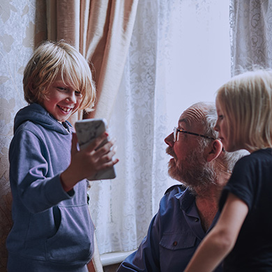A child shows his mobile phone to a man and another child